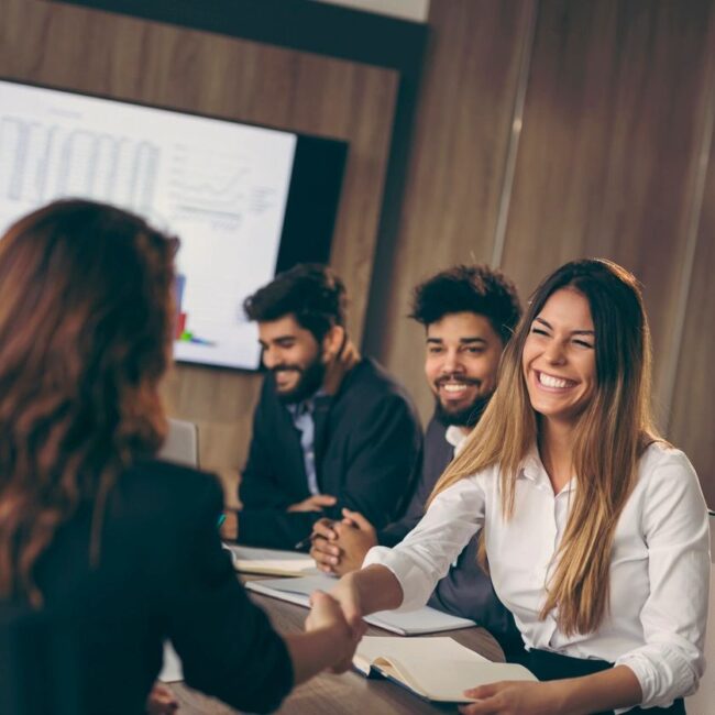 group of professionals in a conference room smiling and shaking hands